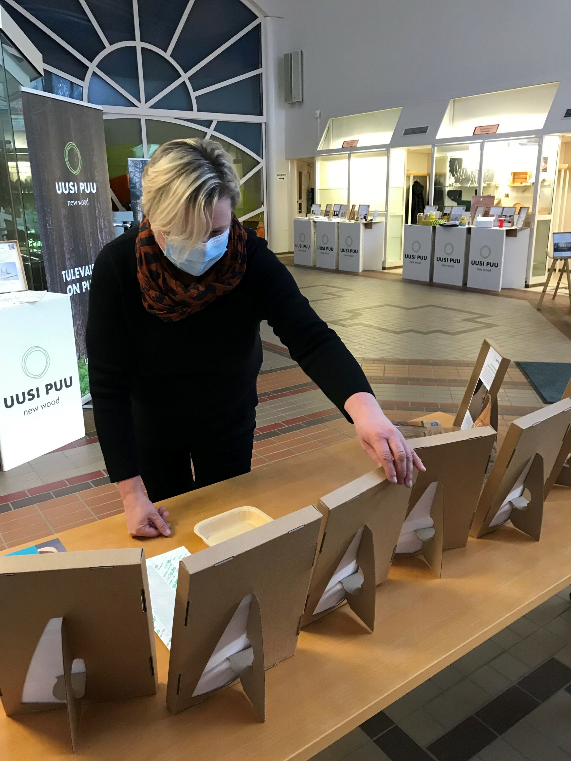 Uusi puu -hankkeen projektipäällikkö Virpi Korhonen asettelee Uusi puu -näyttelyn ratkaisuesimerkkejä pöydälle Äänekosken kaupungintalolla.
