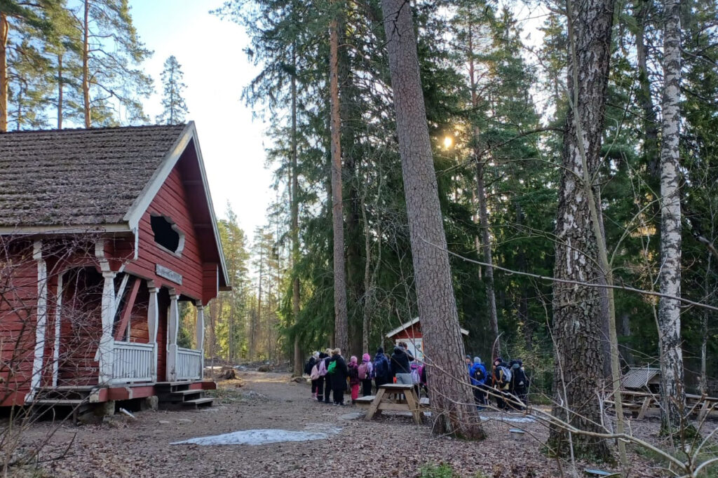 Metsäkoulu Kävyn osallistujat kokoontuvat Tuusulan tutkimusmetsän punaisella mökillä, Professorin pytingillä. Kuva: Suvi Pessala