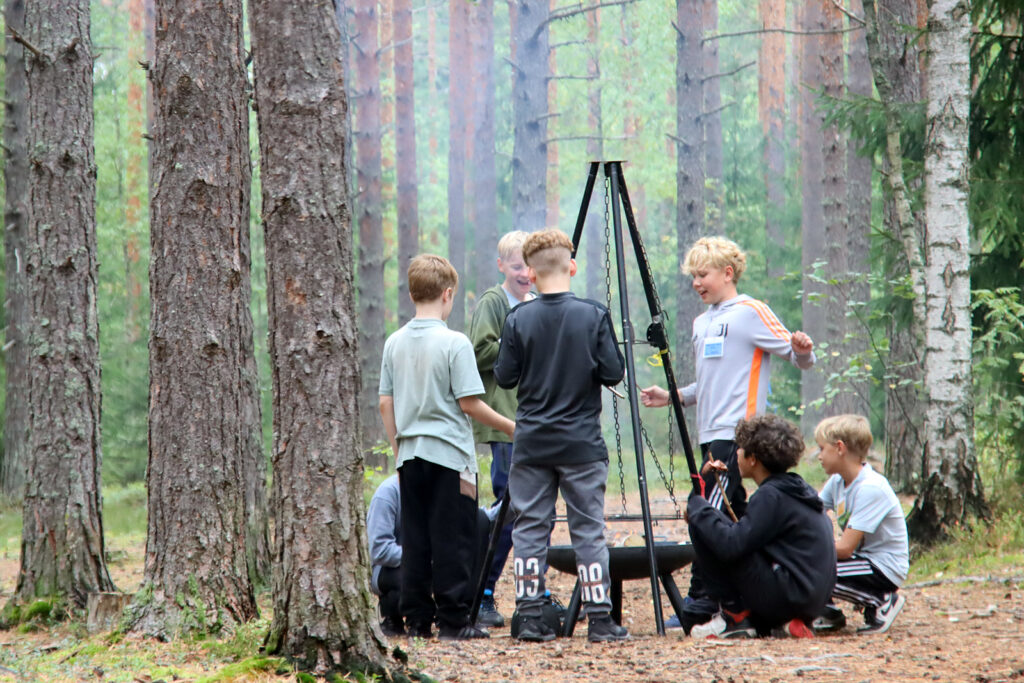 Koululaisia metsässä nuotiolla.